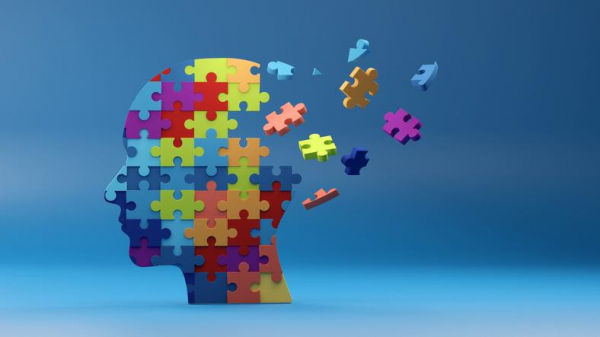 A colorful jigsaw puzzle assembled as a head with several pieces flying away where the brain would be; concept is dementia
